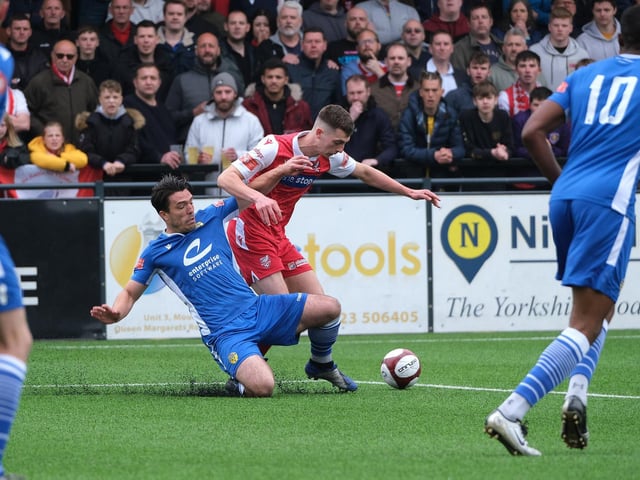 Warrington Town defender Matt Regan looks to nick the ball away ahead of Luca Colville