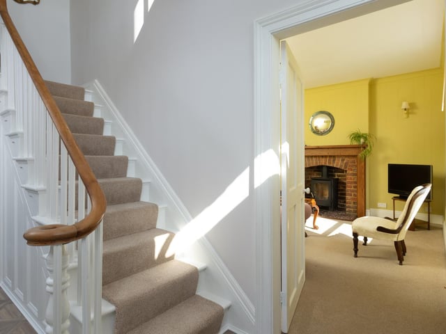 The entrance hallway with staircase featuring carved newel posts and a polished handrail.
