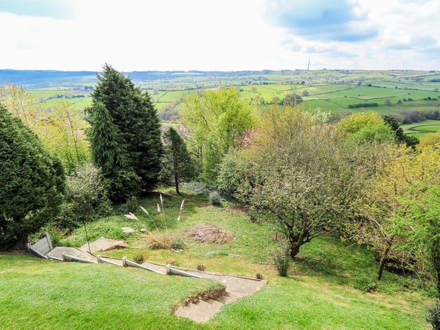 Looking down over lawned gardens with a variety of mature trees.