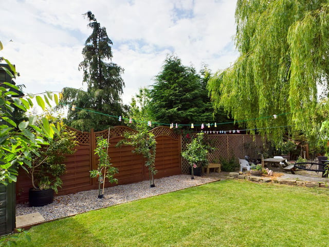There's a sizeable lawned area within the garden, surrounded by trees and fencing.