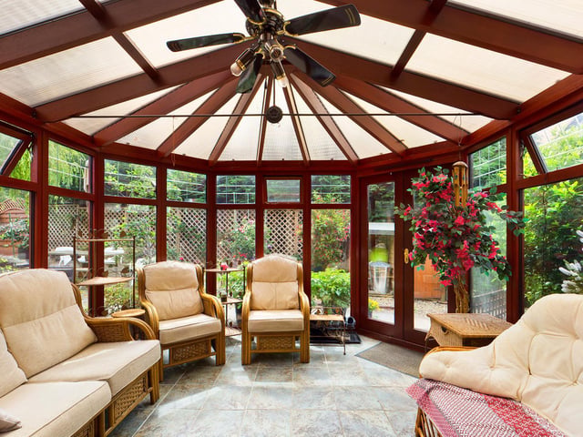 A spacious conservatory, surrounded by greenery.