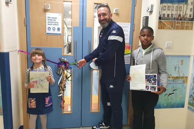 Children in the ward were invited to suggest a new name and draw a picture. Phoebe (age 6) and David (age 11) came up with the winning name - The Rainbow Ward. The youngsters are pictured with Scarborough Athletic manager Jonathan Greening as he cuts the ribbon to officially open the ward.