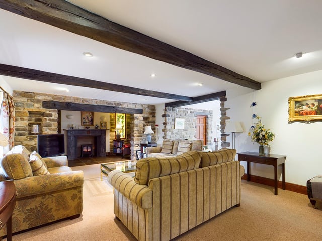 A stunning fireplace feature in this beamed sitting room with open stonework.