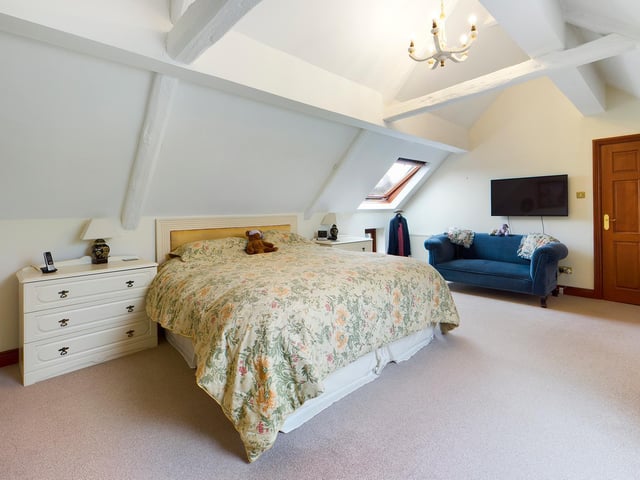 A vaulted ceiling and skylight window in this charming bedroom.