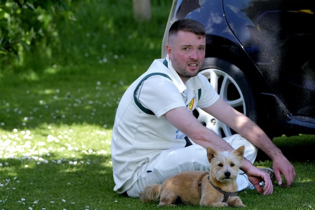 A cricketer watches the action alongside a canine companion