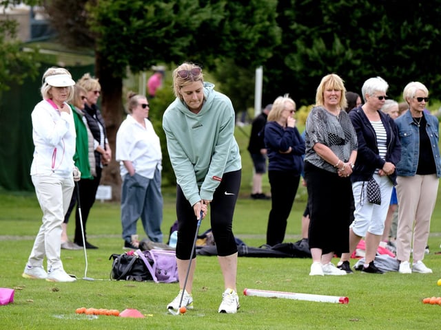 Players look on as a golfer gets ready to tee off