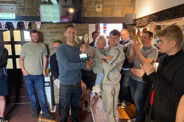 Julie and Mark Welford's son Robbie presents the Blacksmiths team with the trophy after veteran footballers raise £700 for British Heart Foundation in Mark & Julie Welford Memorial Trophy match.