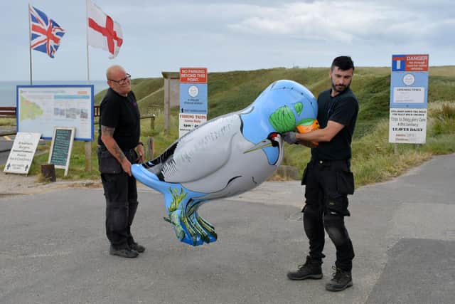 David Millington (left) and Liam Heads of Strata Holdings lifting Skipsea artist Saffron Waghorn’s puffin into place at North Landing, Flamborough.