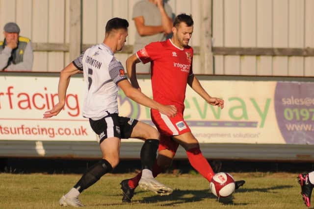 Lewis Dennison on the attack for Bridlington Town, with Boro defender Will Thornton closing in