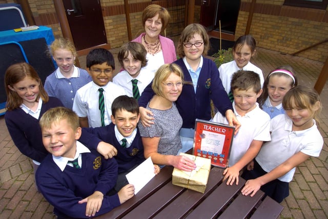 St Peter's School teacher Ursula Campbell, seated centre, says farewell, and is presented with leaving gifts by head teacher Kate Boyes, back centre, and some of the pupils.