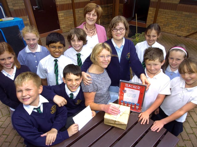 St Peter's School teacher Ursula Campbell, seated centre, says farewell, and is presented with leaving gifts by head teacher Kate Boyes, back centre, and some of the pupils.