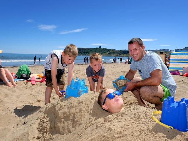 Viktor, Marcel and Dad Lukasz cover Sebastian in sand.