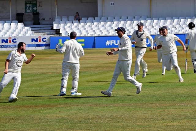 Scarborough CC players rush to celebrate with bowler Dan Robson, far left