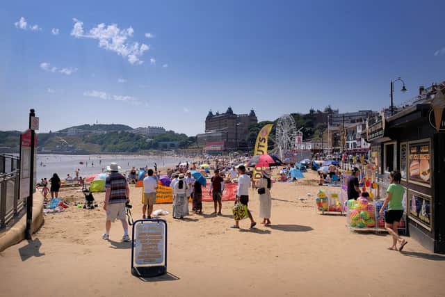 Beachgoers enjoy the seaside with blazing sunshine overhead.