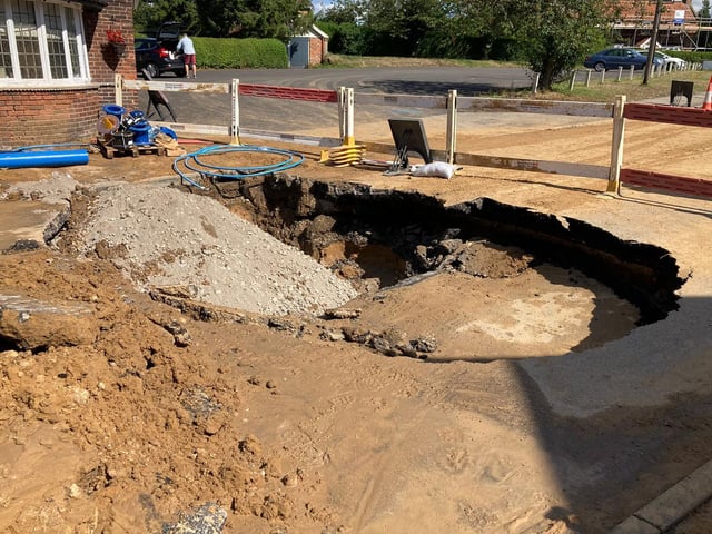 The damage to the road caused by the sinkhole.