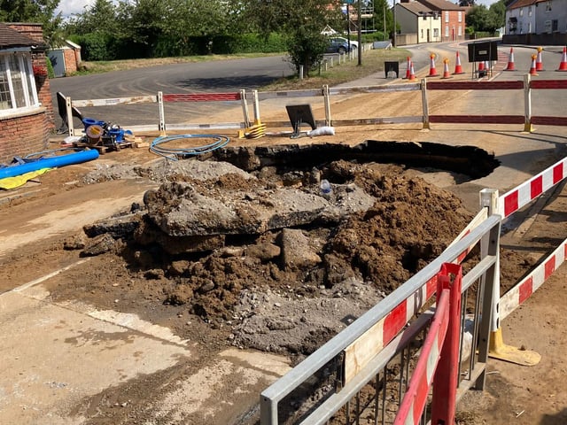 The damage to the road caused by the sinkhole.