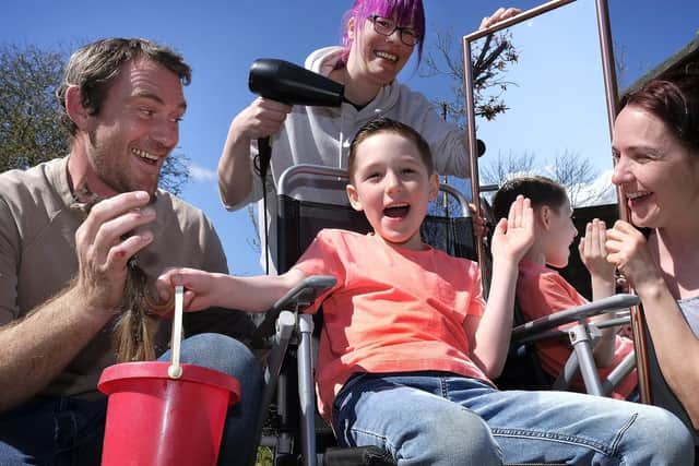 Dara Whitefield completes his charity haircut with Kerry Ward performing the trim, watched by dad Jamie and mum Siobhan.