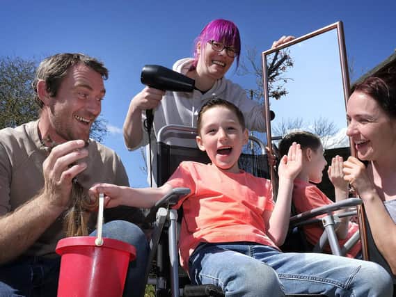 Dara Whitefield completes his charity haircut with Kerry Ward performing the trim, watched by dad Jamie and mum Siobhan.