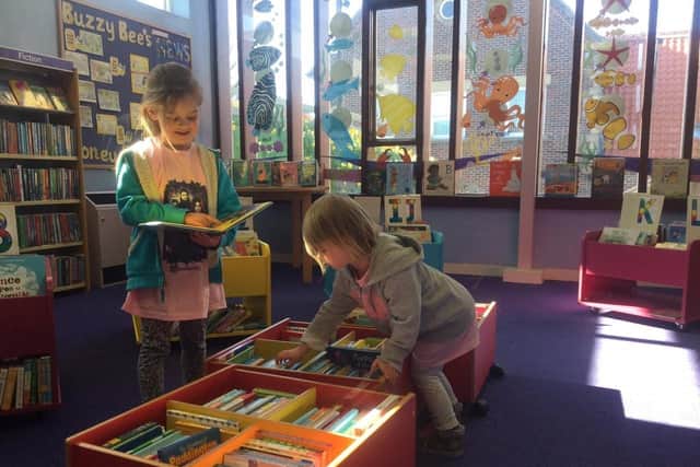 Excited young visitors happily looking for new books in Whitby Library's junior section.