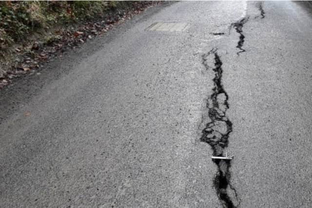 Large cracks appeared in the road after a landslip, making it unsafe.