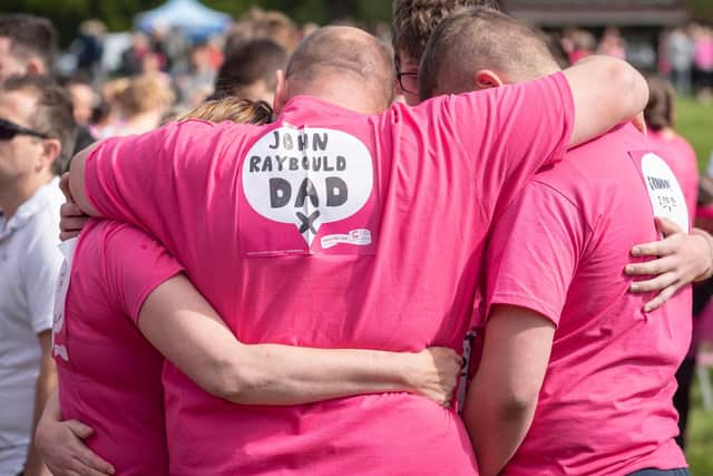 Competitors embrace at the end of a the Race for Life.