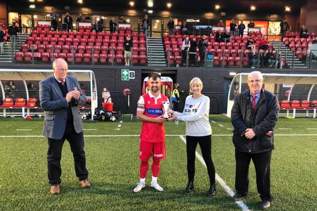 TROPHY WIN: Scarborough Athletic chairman Trevor Bull, left, and his Brid Town counterpart Pete Smurthwaite, look on while Wendy Danby presents Boro midfielder Ryan Watson with the Dave Holland Trophy after the hosts earned a 3-1 win on Tuesday evening