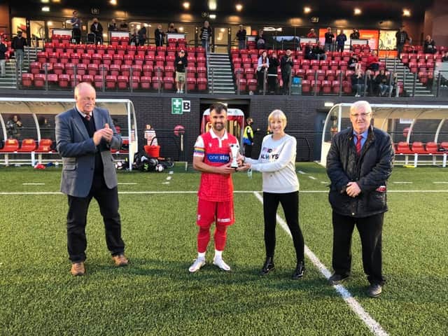 TROPHY WIN: Scarborough Athletic chairman Trevor Bull, left, and his Brid Town counterpart Pete Smurthwaite, look on while Wendy Danby presents Boro midfielder Ryan Watson with the Dave Holland Trophy after the hosts earned a 3-1 win on Tuesday evening