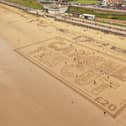 A group of about 80 individuals made up of families who rely on universal credit to put food on the table and pay their bills travelled from Chesterfield to help create a giant £20 note in the sand. Photo courtesy of Sand In Your Eye