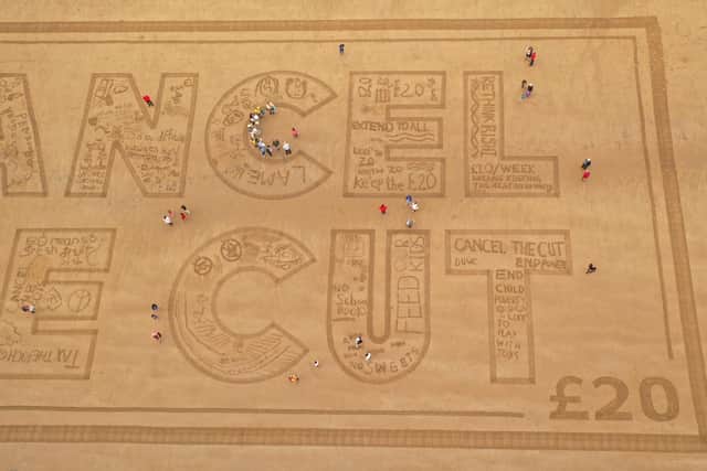 The sand art was then washed away by the tide, representing the universal credit cut scheduled for Thursday, September 30. Photo courtesy of Sand In Your Eye