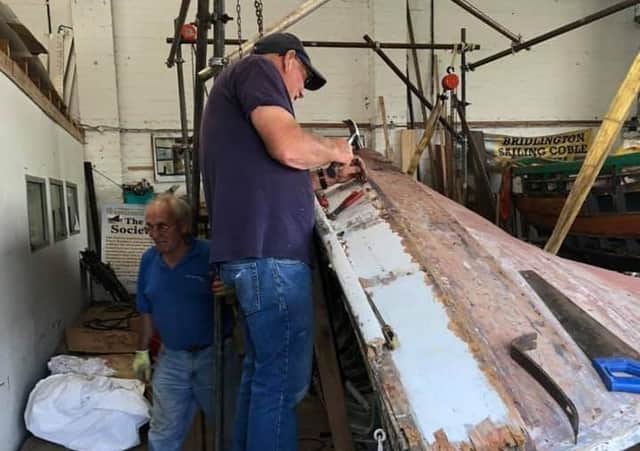 John Clarkson and Malcolm Smales get to work on the coble Venus inside the workshop at Beck Hill in Bridlington.