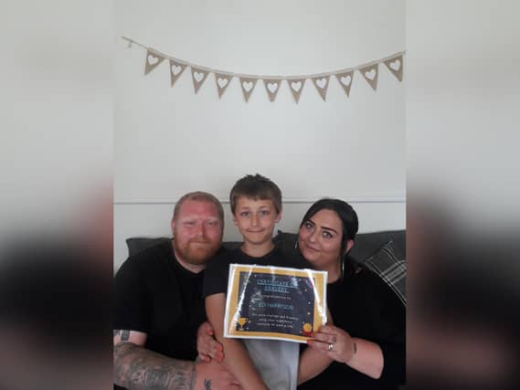 Young hero Eli Harrison with his dad Ian and mum Kayleigh. Eli is pictured with a certificate Kayleigh’s colleagues made for him when they heard about his brave actions.