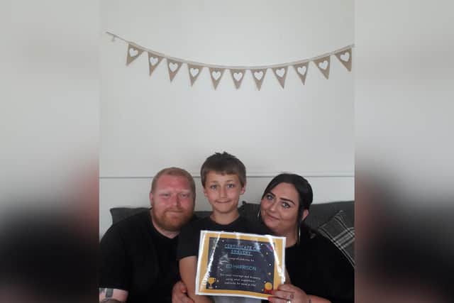 Young hero Eli Harrison with his dad Ian and mum Kayleigh. Eli is pictured with a certificate Kayleigh’s colleagues made for him when they heard about his brave actions.