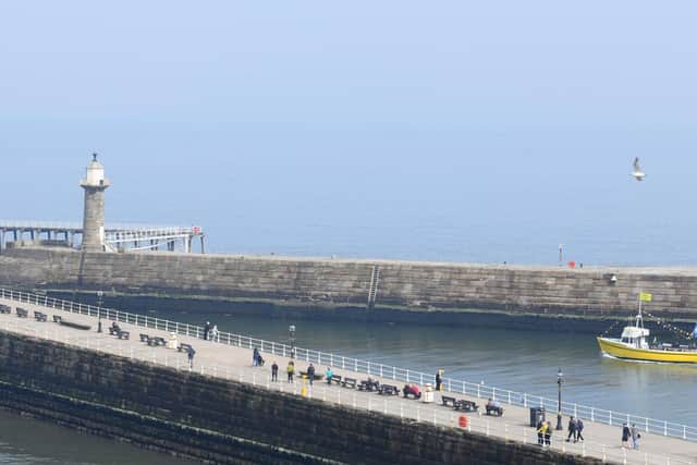 People enjoying a walk along the pier at Whitby in hazy sunshine.
Picture by Gary Longbottom.