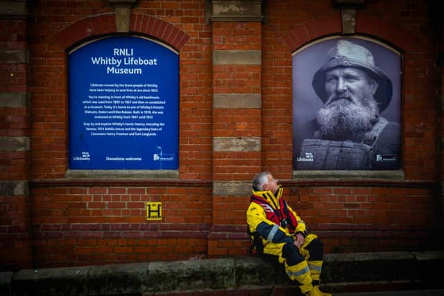 Whitby Lifeboat museum curator in a modern day RNLI kit outside Whitby Museum and a photograph of Henry Freeman, the only survivor of the Whitby Lifeboat disaster of February 1861 as he was wearing an early cork lifejacket.