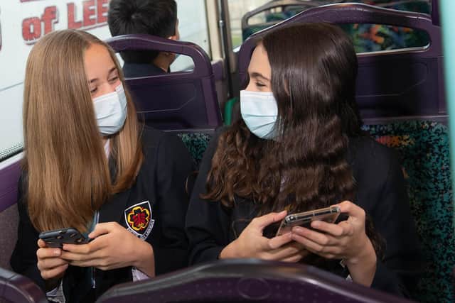 Students Evie and Harriet wear face masks on the school bus.