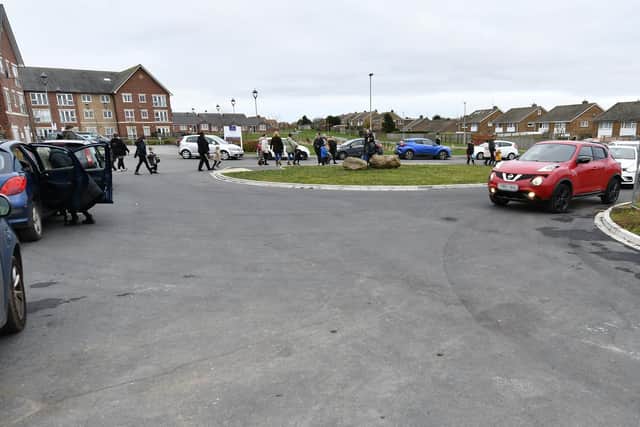 Parents and children passing between parked cars at Overdale School