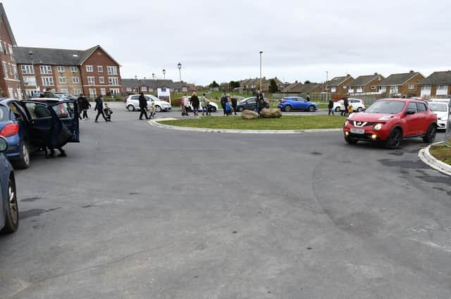 Parents and children passing between parked cars at Overdale School
