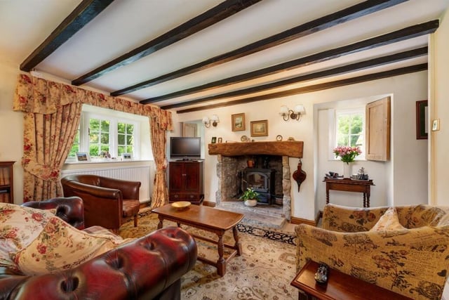 A beamed sitting room with rustic fireplace.
