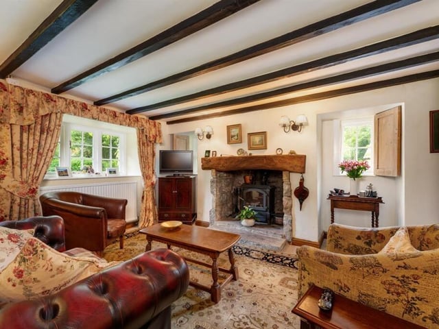 A beamed sitting room with rustic fireplace.