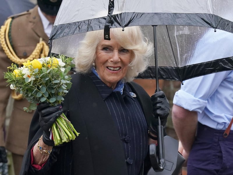 The Queen Consort waves at the crowd after receiving a beautiful bunch of flowers.