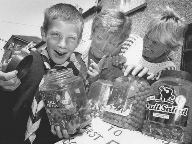 At the Filey Edwardian Street Party in Queen Street, Filey, sweet-toothed cub scout Mark Womersley, pictured with his mum Lesley, and friend Susan Pinder, right, take charge of the Filey Scouts stall. The street party took place back in July, 1995. 