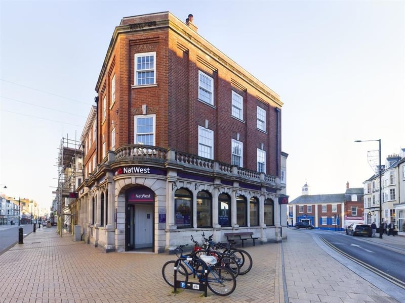 A stylish one-bed, second-floor apartment in a central town location. The building was used as a bank and was converted to apartments in 2014. This apartment has stunning original features, with many amenities on the doorstep and close to both harbour and foreshore.
Accommodation with Upvc double glazing and gas central heating, comprises a communal entrance with door phone system, and stairs to the first floor. An inner hall has access to insulated loft space. The kitchen has fitted units, an electric oven, gas hob, and integrated fridge freezer, plus a utility room. There's a lounge with log burning stove, and three sash windows, a double bedroom, and a stylish shower room. The apartment is leasehold, 125 years from 2014 with a £45 monthly charge which includes ground rent, and maintenance and building insurance. Not to be used for holiday lets.