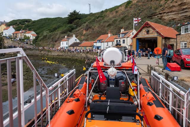 Crowds line the beck side vantage points as the annual duck race reaches the finish line - Image: RNLI/James Stoker