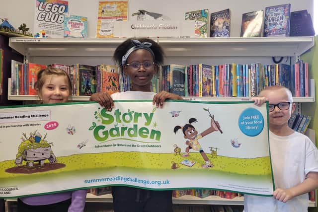 From left, Rita, Sharon and Lotan from Bentham Community Primary School, showing off the Story Garden Summer Reading Challenge banner.
