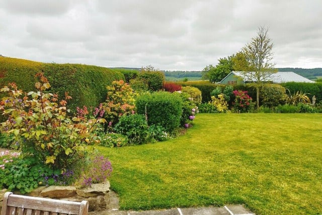 A stunning lawned garden with deep filled borders.