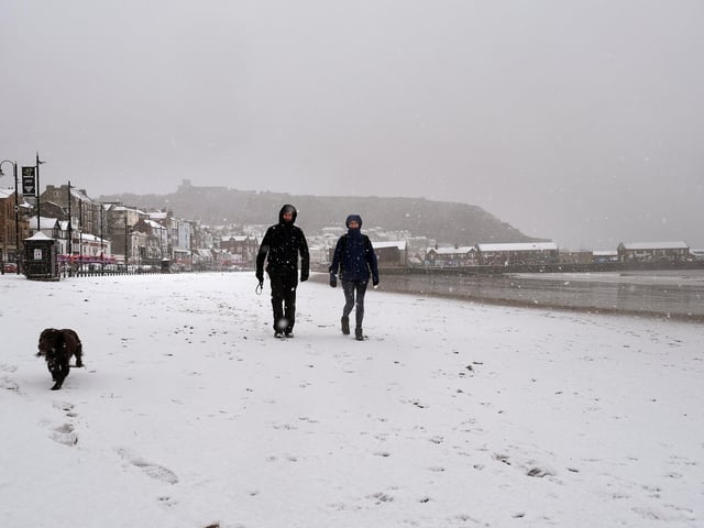 Snow falling on South Bay beach as walkers enjoy a winter scene