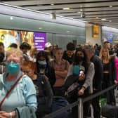Travellers wait in a long queue to pass through the security check. (Photo by Carl Court/Getty Images)