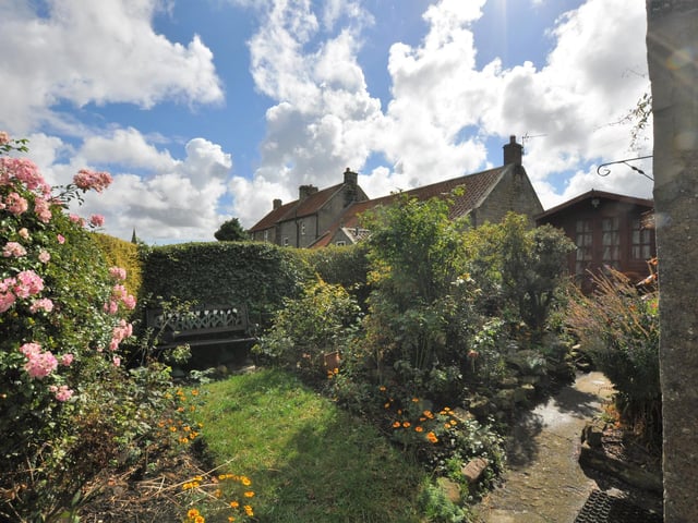 A lawn, and established trees, plants and flowers fill the property's garden area.