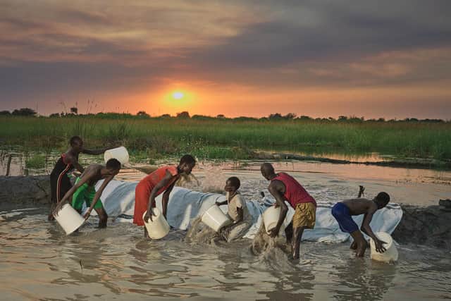 An entire family works into the night trying to scoop out flood water that had poured onto their land.
