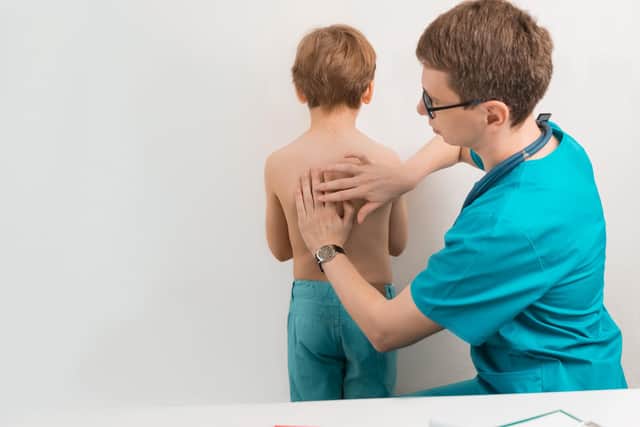 A doctor performing percussion of the lungs and heart in a clinical examination. Photo: StockAdobe